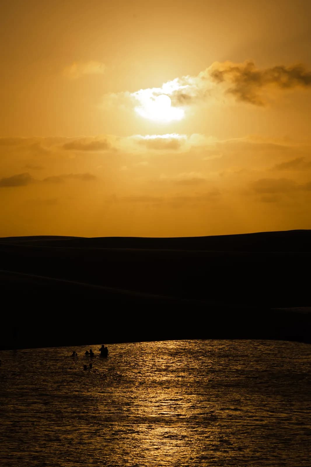Pôr do sol nos Lençóis Maranhenses, com o sol refletido na água