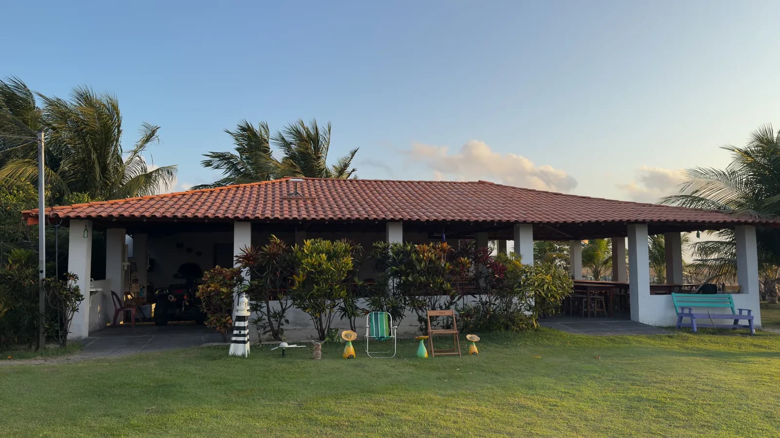 Fachada do Rancho e Restaurante Canto de Atins no fim da tarde, com telhado de barro, coqueiros e gramado